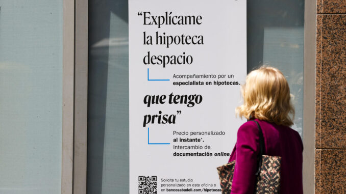 Una mujer ante un cartel bancario sobre las hipotecas. EFE/Luis Tejido
