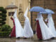 Unos nazarenos de la Hermandad de La Sentencia se protegen de la lluvia con paraguas mientras caminan hacia su templo en Córdoba (Andalucía). EFE/ Rafa Alcaide