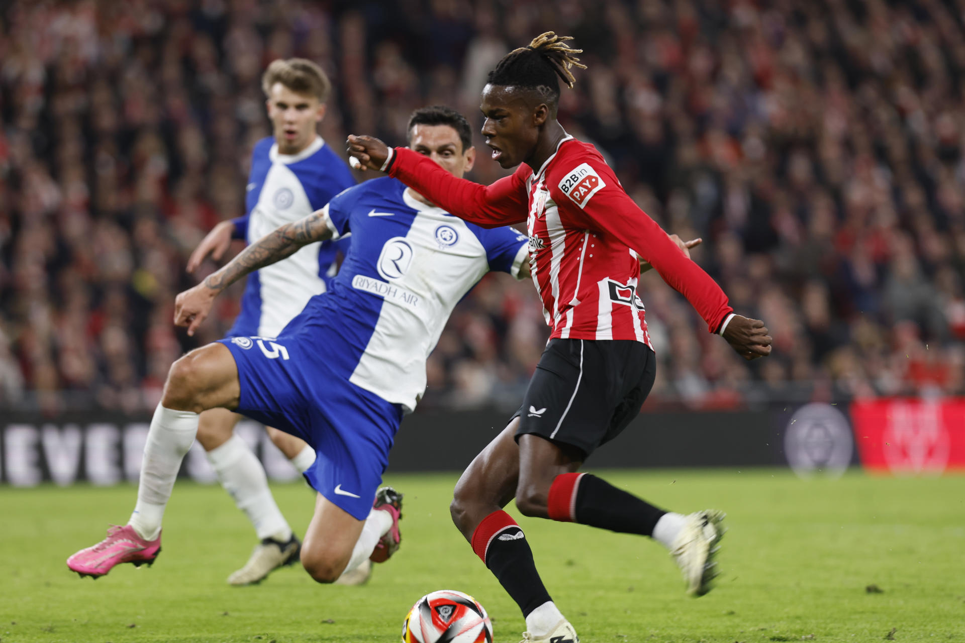 El centrocampista del Athletic Club Nico Williams (d) controla el balón junto a Stefan Savic, del Atlético de Madrid, durante el partido de vuelta de semifinales de la Copa del Rey que Athletic Club de Bilbao y Atlético de Madrid disputan este jueves en el estadio de San Mamés, en Bilbao. EFE/Miguel Tona
