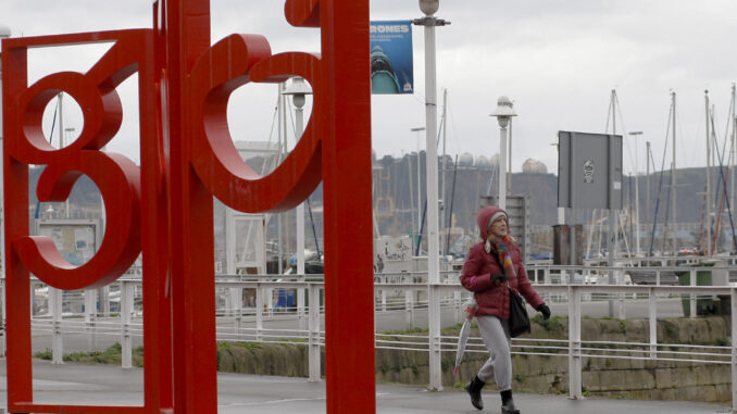 Una mujer camina por el puerto deportivo de Gijón este lunes. EFE/ Juan González
