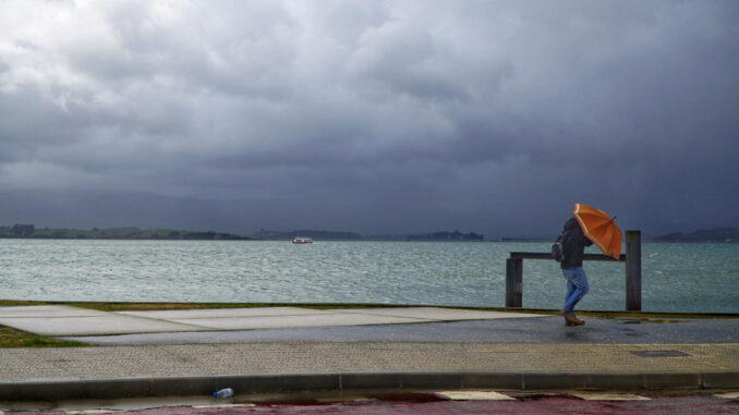 Una persona camina junto al mar con paraguas durante una jornada lluviosa este domingo, en Santander. EFE/Román G. Aguilera
