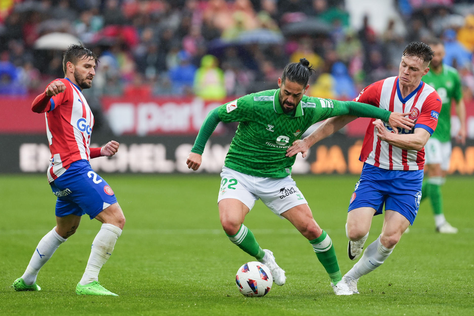 Los jugadores del Girona Portu (i) y Viktor Tsygankov disputan un balón ante el centrocampista del Betis Isco (c), durante el partido de la jornada 30 de LaLiga EA Sports entre el Girona y el Betis, este domingo en el estadio de Montilivi en Girona.-EFE/ David Borrat
