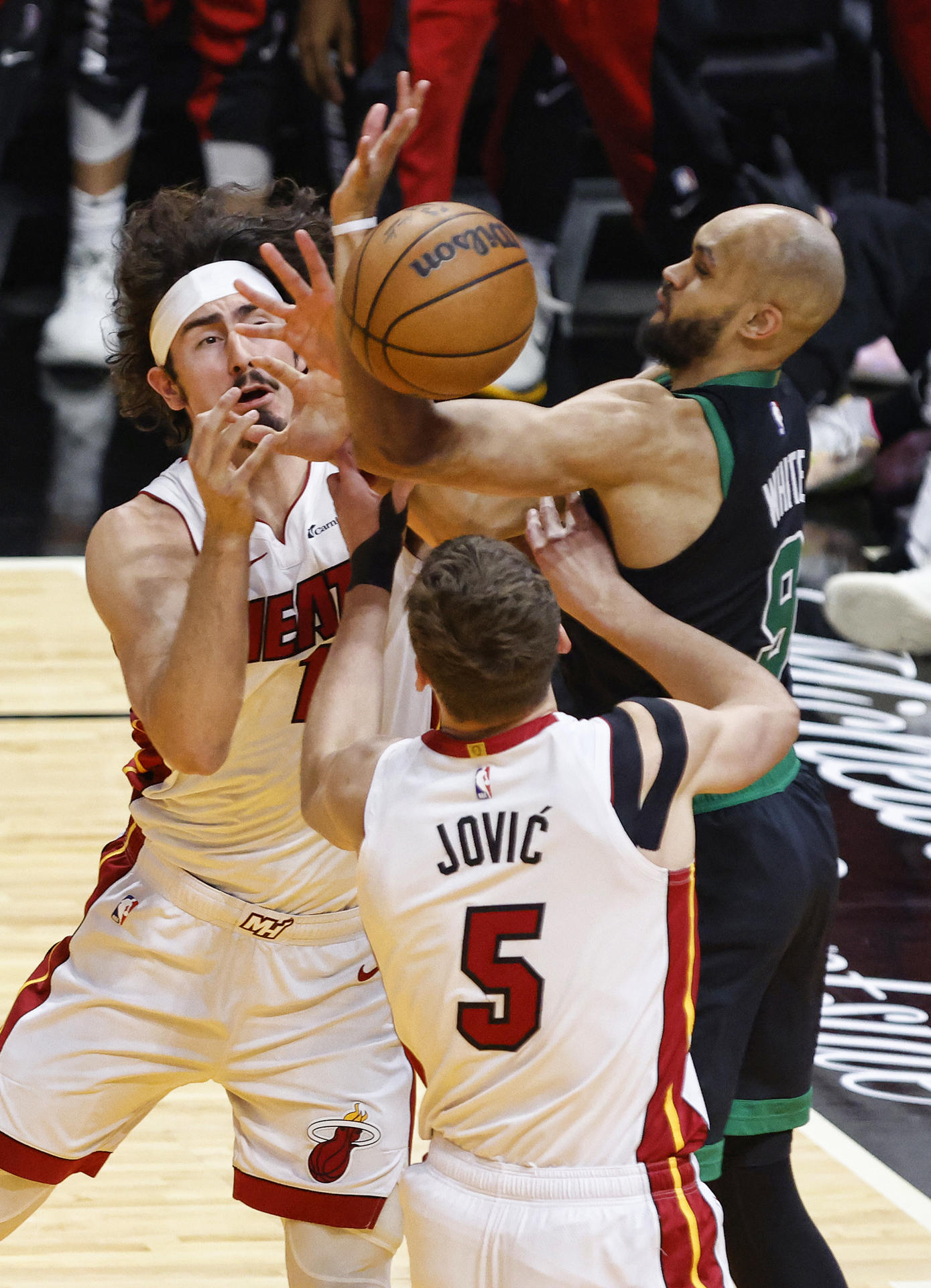 El armador de los Celtics, Derrick White (d), disputa un balón con Jaime Jaquez Jr. (i) y Nikola Jovic (c) de los Heat en el partido jugado este lunes en el Kaseya Center de Miami (Florida) que dejó a la franquicia de Boston con una venta de 3-1 en la serie de primera ronda de los 'playoffs' de la NBA. EFE/ Rhona Wise.
