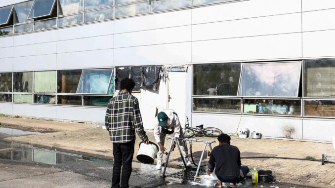 Unos inmigrantes lavan platos fuera de un edificio de oficinas abandonado en Vitry-sur-Seine, cerca de París, Francia, el 8 de abril de 2024 (publicado el 11 de abril de 2024). FE/EPA/MOHAMMED BADRA
