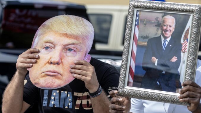 Fotografía de archivo donde se aprecia dos personas con un retrato de Biden y una máscara de Trump. EFE/EPA/CRISTOBAL HERRERA-ULASHKEVICH
