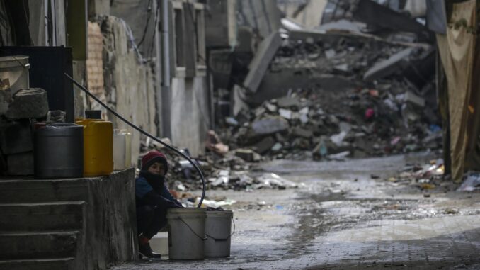 Un niño llena un cubo con agua entre los escombros de estructuras destruidas durante una operación militar israelí en el campo de refugiados de Al Nusairat, en el sur de la Franja de Gaza, 19 de febrero de 2024. EFE/EPA/MOHAMMED SABLE
