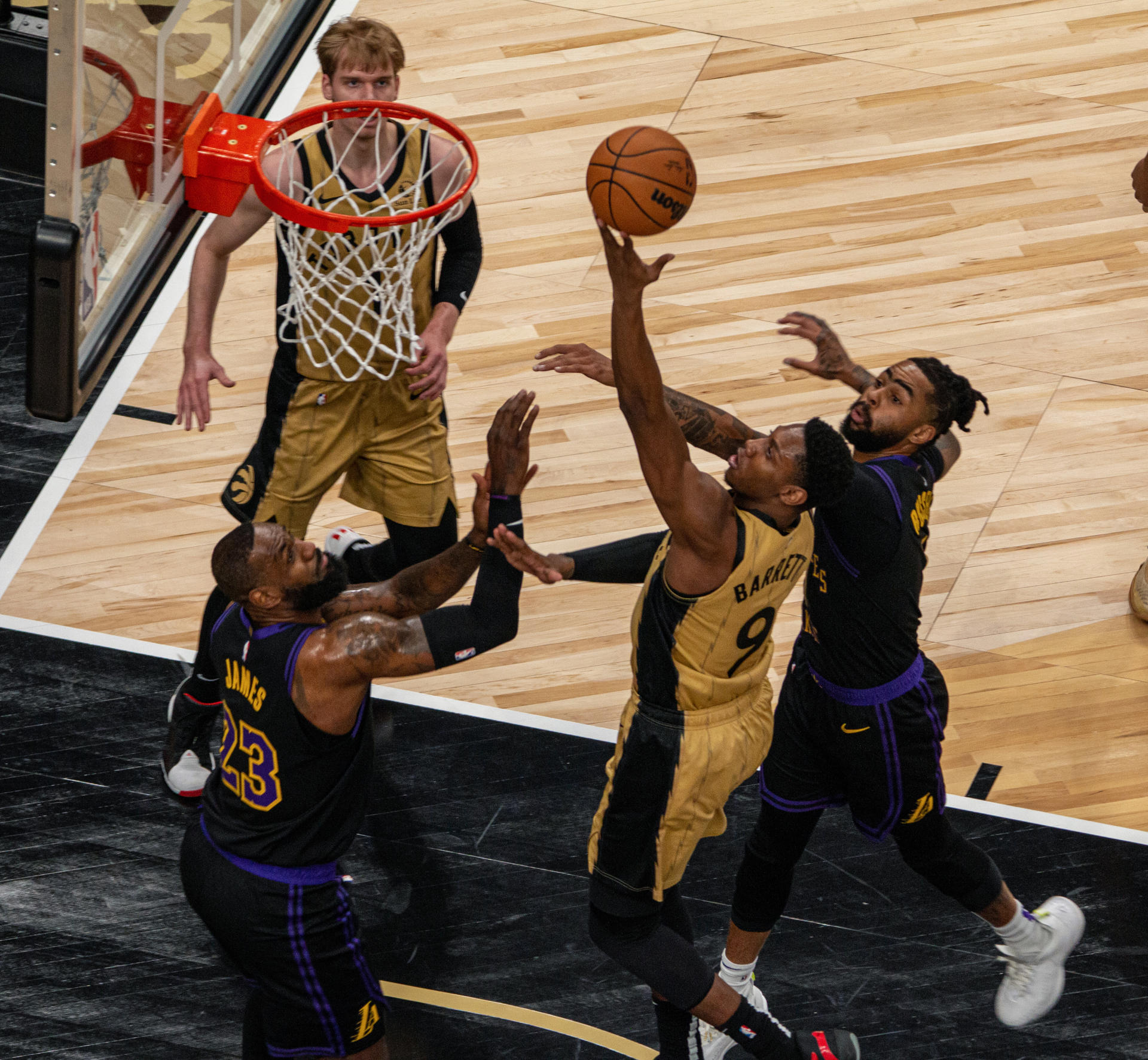 El jugador de los Toronto Raptors RJ Barrett en una entrada a canasta con la oposición de LeBron James y D'Angelo Russell, de Los Angeles Lakers, durante un partido en el Scotiabank Arena en Toronto (Canadá). EFE/ Julio César Rivas
