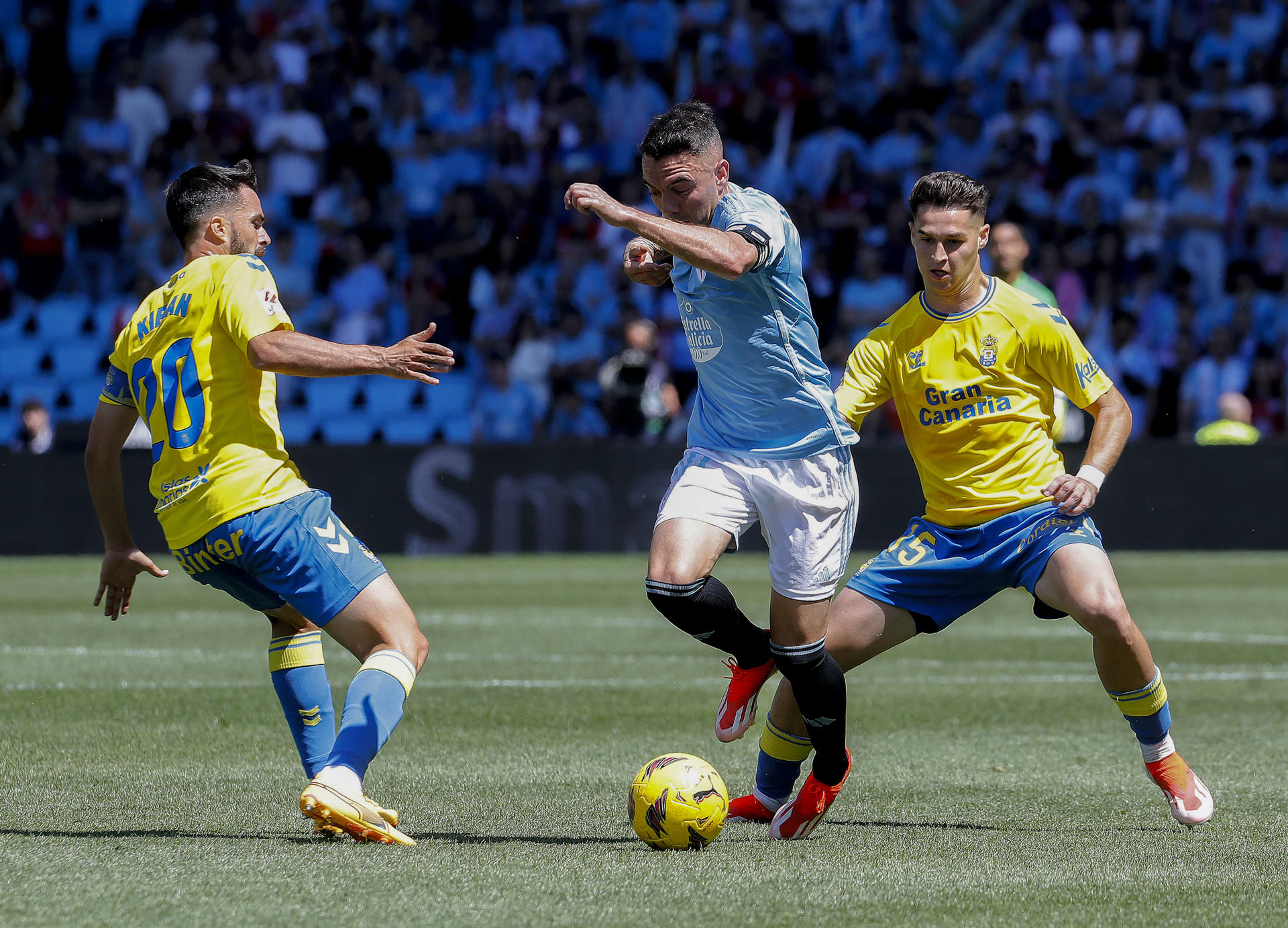 El jugador del Celta de Vigo Iago Aspas (c) disputa el balón con Kiriam y Mármol (d), de Las Palmas, durante el partido de Liga celebrado este sábado en el estadio Balaídos de Vigo. EFE / Salvador Sas
