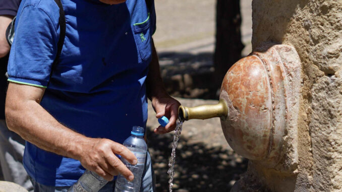 Una persona rellena una botella de agua en la fuente del Patio de los Naranjos este miércoles, en Córdoba. EFE/ Rafa Alcaide
