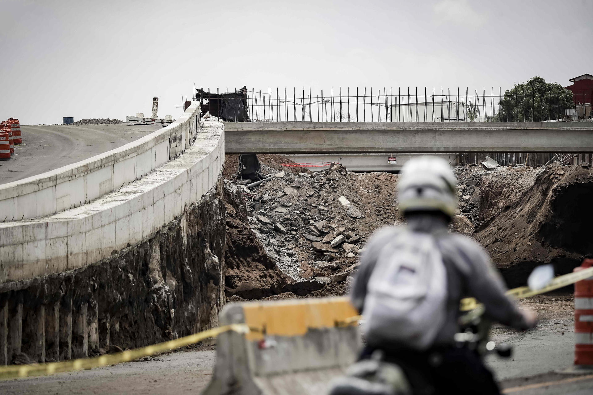 Un motociclista detenido frente a una carretera en construcción este martes, en San José (Costa Rica). EFE/ Jeffrey Arguedas
