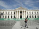 Un hombre camina frente al Palacio Nacional mientras se realizan los preparativos para la ceremonia de investidura del segundo mandato de Nayib Bukele, este jueves en San Salvador (El Salvador). EFE/ Rodrigo Sura