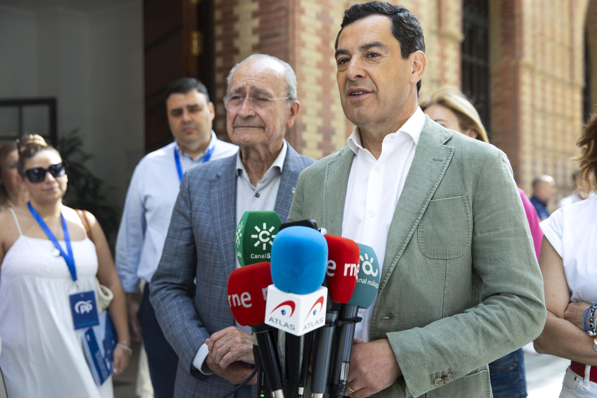 El presidente del PP andaluz y de la Junta, Juanma Moreno, atiende a los medios acompañado por el alcalde de Málaga, Francisco de la Torre (c-i), tras votar en las elecciones al Parlamento Europeo en el colegio Sagrado Corazón de Málaga, este domingo. EFE/Jorge Zapata
