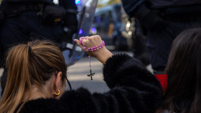 Imagen de archivo (18/11/2023) de una joven sosteniendo un rosario con la Cruz de la Victoria (Asturias)durante una manifestación en contra de la amnistía. EFE/ Daniel González
