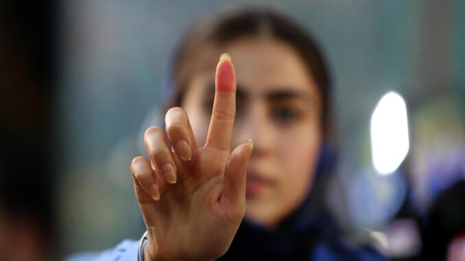 Una chica iraní enseña su dedo manchado de tinta después de votar en Teherán para las elecciones presidenciales. EFE/EPA/Stringer
