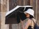 Una turista se protege del calor con parasol mientras pasea por el centro de la ciudad de Valencia este miércoles. EFE/Ana Escobar