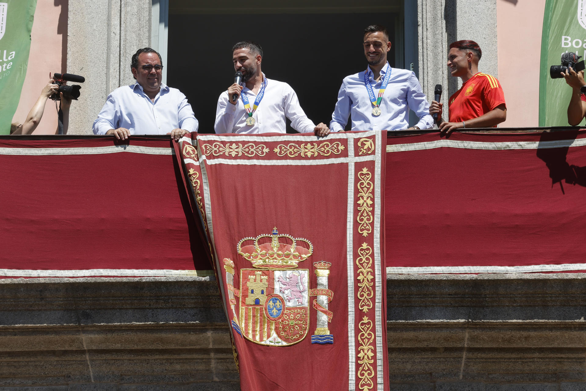 Los jugadores de la selección española de fútbol Dani Carvajal (c-i) y Joselu (c-d), vecinos de Boadilla del Monte, junto al alcalde de la localidad, Ignacio Vázquez Casavilla (i), mientras saludan a los aficionados desde el balcón del Ayuntamiento de Boadilla con motivo de su visita para celebrar la reciente victoria del equipo en la Eurocopa. EFE/ Zipi
