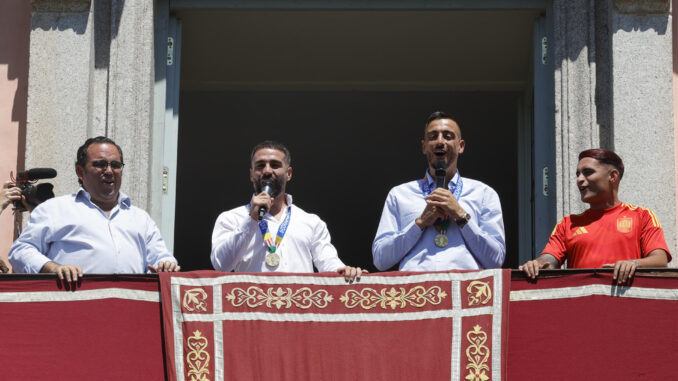 Los jugadores de la selección española de fútbol Dani Carvajal (c-i) y Joselu (c-d), vecinos de Boadilla del Monte, junto al alcalde de la localidad, Ignacio Vázquez Casavilla (i), mientras saludan a los aficionados desde el balcón del Ayuntamiento de Boadilla con motivo de su visita para celebrar la reciente victoria del equipo en la Eurocopa. EFE/ Zipi
