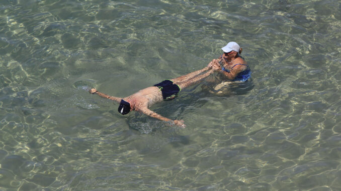 Dos personas se refrescan en la playa del Mal Pas de Benidorm en este último viernes de julio en el que se siguen registrando temperaturas muy altas en gran parte del país. EFE/Morell
