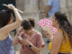 Tres personas se protegen del calor con abanicos mientras pasea por el centro de la ciudad de Valencia este martes. EFE/Kai Försterling