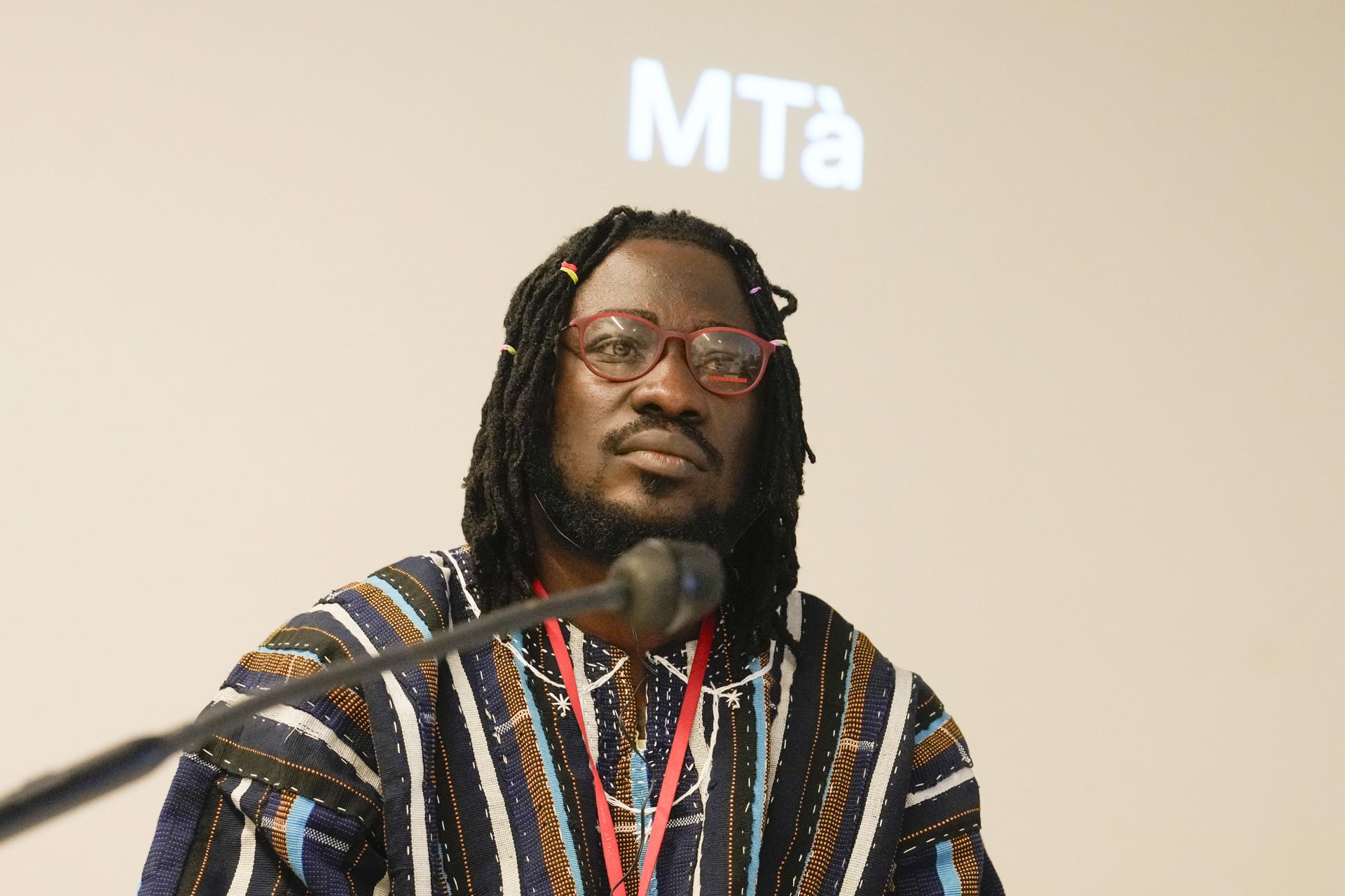 -El artista ghanés Attukwei Clottey durante la presentación este lunes, en que la Fundació Tàpies pasa a denominarse a partir de ahora Museu Tàpies, del proyecto, 'Más allá de la piel', que se inaugurará mañana y con el que revestirá la fachada del edificio, diseñado por Lluís Domènech i Montaner, con una segunda piel, compuesta de teselas realizadas con material de desecho. EFE/ Enric Fontcuberta
