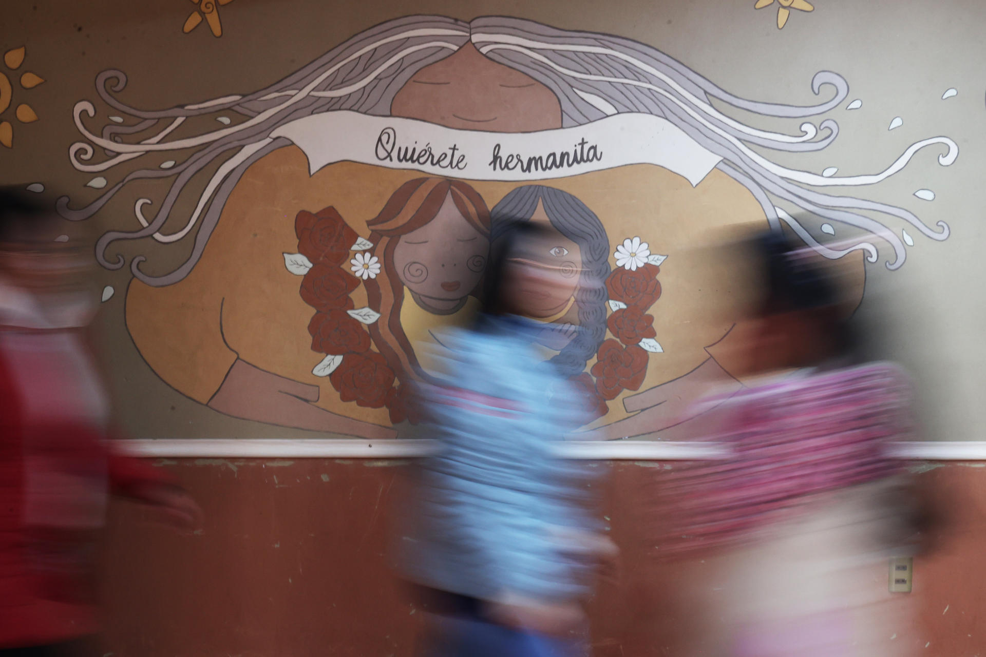 Fotografía del 22 de julio de 2024 de mujeres pasando frente a un mural en la fundación Munasim Kullakita, en La Paz (Bolivia). EFE/ Luis Gandarillas
