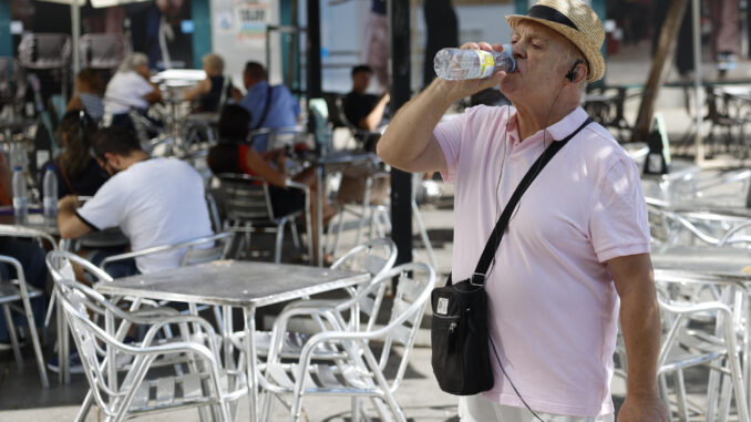 Un hombre bebe agua esta mañana en Madrid, donde las temperaturas permanecen altas. EFE/ Mariscal
