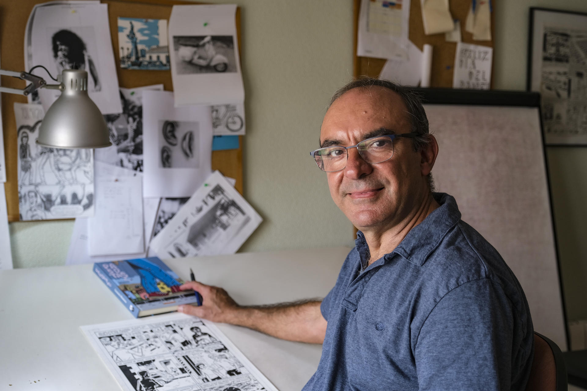 El alicantino Carmelo Manresa en su estudio de Torrevieja junto a un ejemplar de su última novela gráfica, 'Pasotas', donde trata el problema de la heroína en la juventud durante la década de 1980. EFE/Pablo Miranzo
