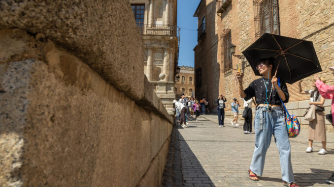 Una turista pasea protegida por un paraguas este lunes en Toledo, donde hay aviso naranja por altas temperaturas. EFE/Ángeles Visdómine
