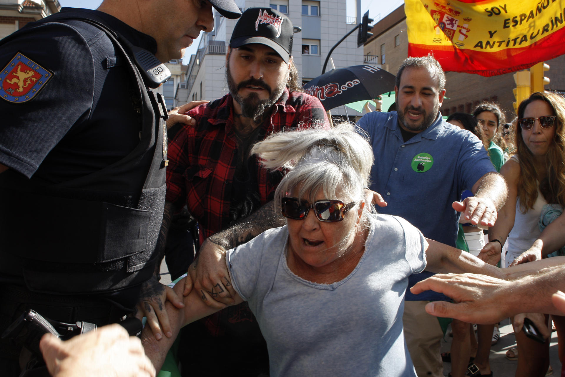 Una manifestante forcejea con la Policía este jueves al intentar forzar la valla que protegía la plaza de toros de Gijón. Varios centenares de personas, 1.200 según la Policía Nacional, han participado en la manifestación convocada por la plataforma Asturies Antitaurina para reclamar la abolición de las corridas de toros, en coincidencia con la primera jornada de la feria de Begoña. EFE/Juan González.
