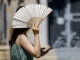 En la imagen una mujer se protege del intenso calor con un abanico, este viernes en las calles de Valencia. EFE/Ana Escobar