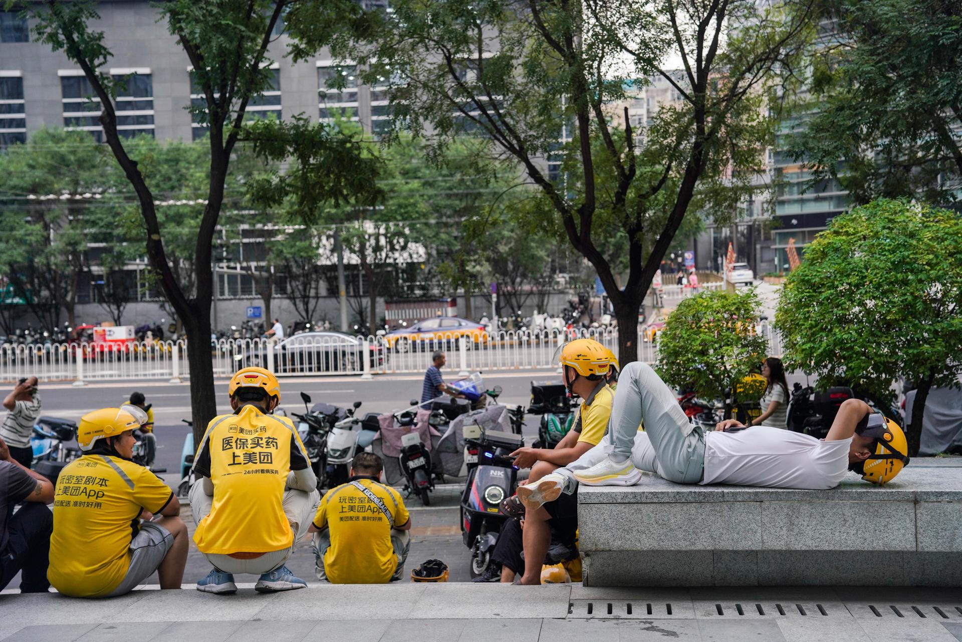 repartidores descansan delante d eun centro comercial en Pekín. EFE/EPA/WU HAO
