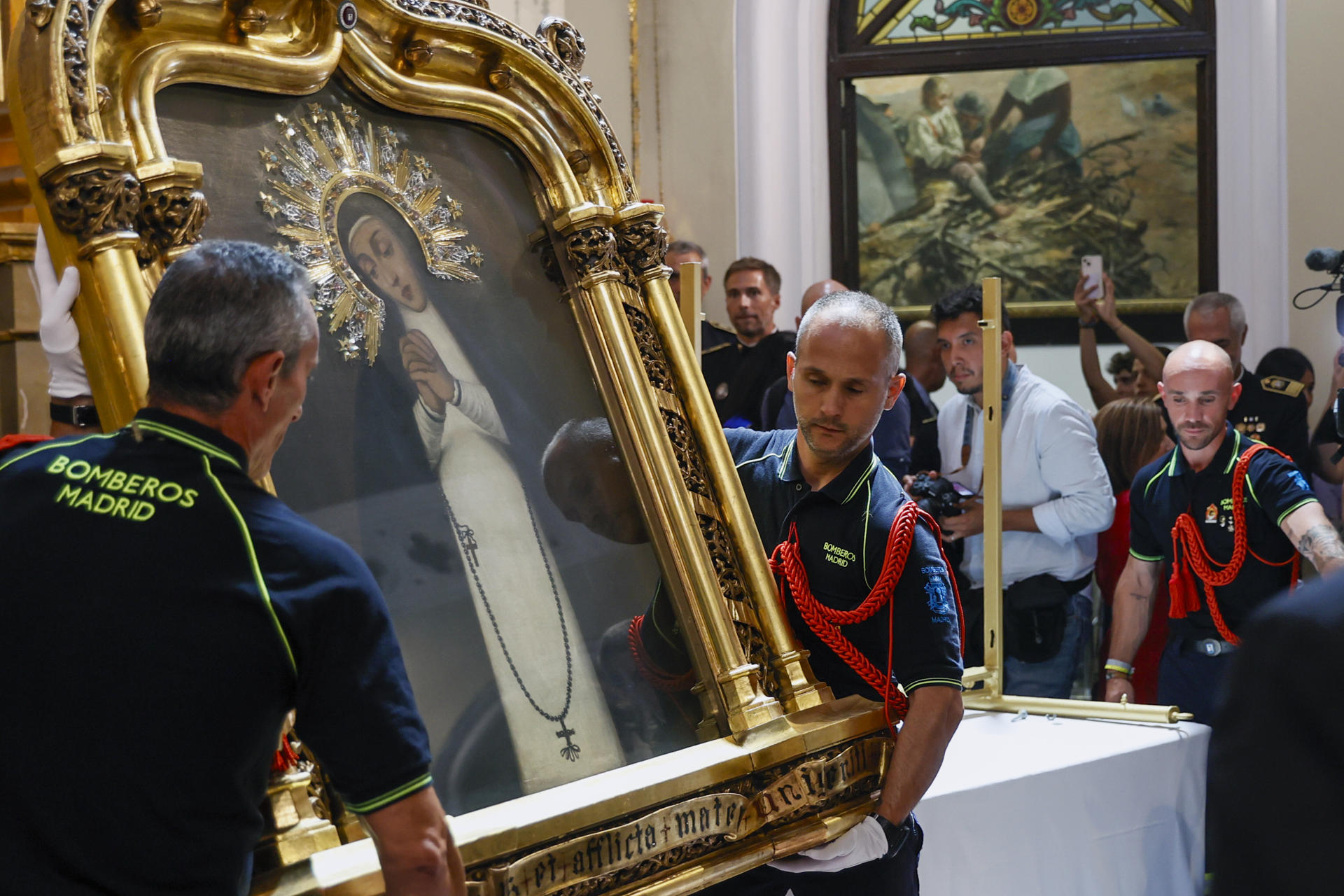 Bajada del cuadro de la Virgen por el piquete del Cuerpo de Bomberos del Ayuntamiento de Madrid, este jueves en la Iglesia de la Virgen de la Paloma, en Madrid. EFE/ Fernando Alvarado
