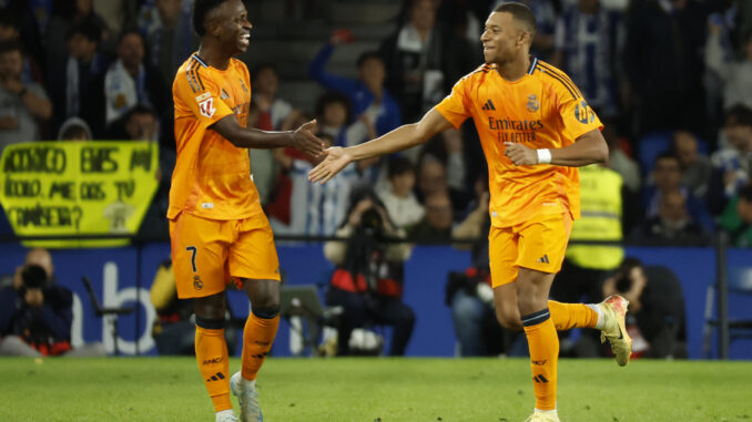 El delantero del Real Madrid Kylian Mbappé (d) celebra su gol durante el partido de la quinta jornada de LaLiga EA Sports entre la Real Sociedad y el Real Madrid, este sábado en el Real Arena de San Sebastián (País Vasco). EFE/Juan Herrero
