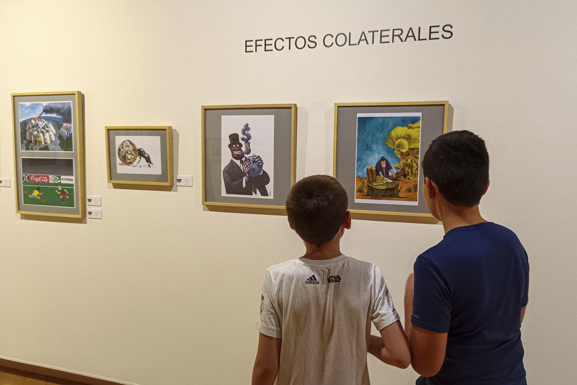 Dos niños visitan ‘Milmillonarios’, la exposición central de la XXXI Muestra Internacional de las Artes del Humor de Alcalá de Henares, en la que se representa a través de viñetas y el doble sentido la codicia, la opulencia, la avaricia y el descaro de los más pudientes. EFE/ Guilllermo Martínez
