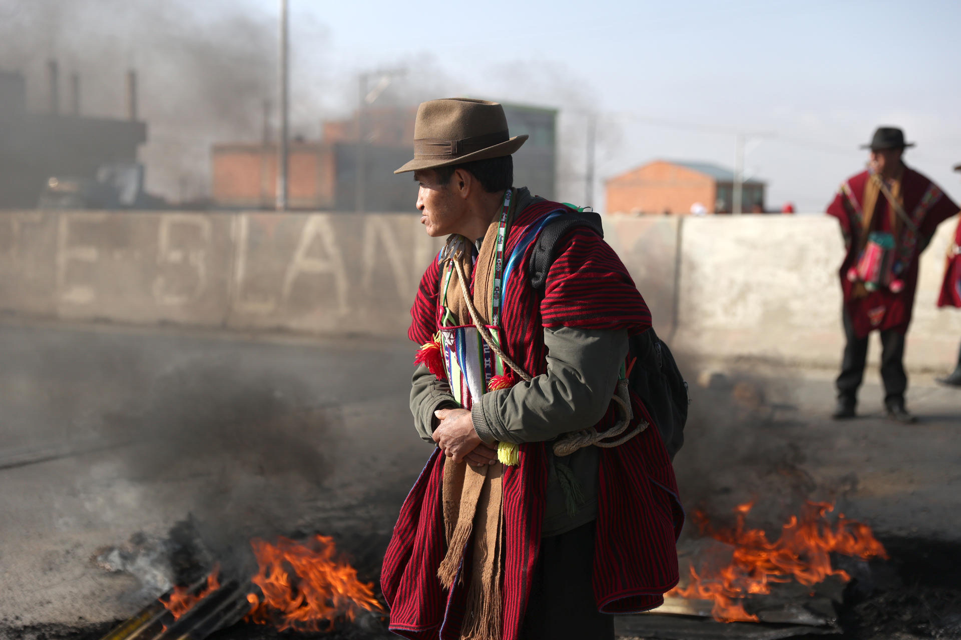 Indígenas bloquean una vía incinerando escombros durante una protesta este lunes en la ciudad de El Alto (Bolivia). Los indígenas llamados 'ponchos rojos' del altiplano de Bolivia, iniciaron este lunes un bloqueo de caminos para exigir la renuncia del presidente Luis Arce y del vicepresidente David Choquehuanca, por la falta de dólares y combustible además de acusarles de promover la división de las organizaciones sociales. EFE/Luis Gandarillas
