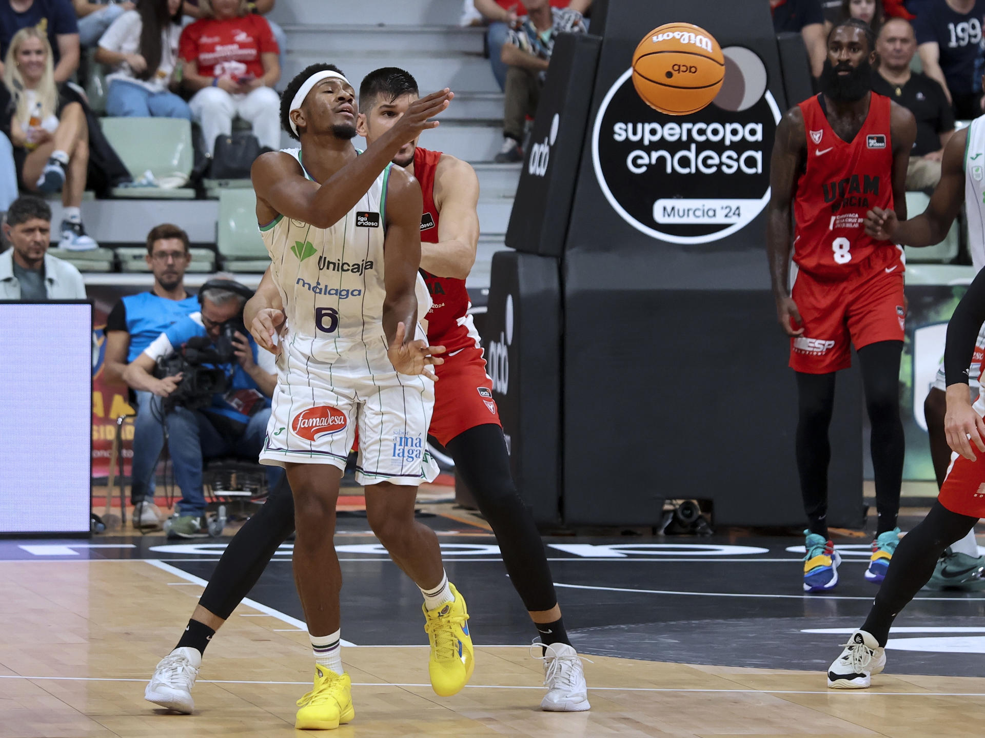 El alero del Unicaja Kameron Taylor (i) con el balón ante Marco Mirko, del UCAM Murcia durante el segundo partido de semifinales de la Supercopa Endesa que disputaron en el Palacio de los Deportes de Murcia. EFE/Juan Carlos Caval
