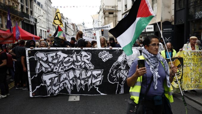 Una mujer enarbola una bandera palestina en la manifestación convocada en París por partidos de izquierda para pedir la dimisión del presidente francés. Enmanuel Macron (Protestas, Francia) EFE/YOAN VALAT
