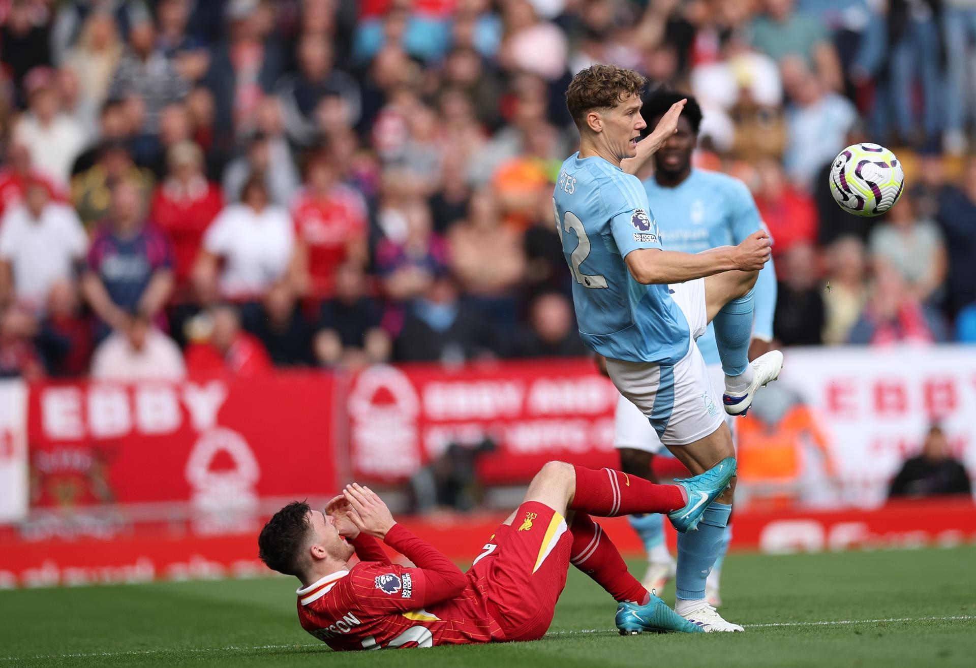 El jugador del Liverpool Andrew Robertson cae al césped ante un jugador del Nottingham Forest durante el partido de la Premier League jugado en Anfield. EFE/EPA/ADAM VAUGHAN
