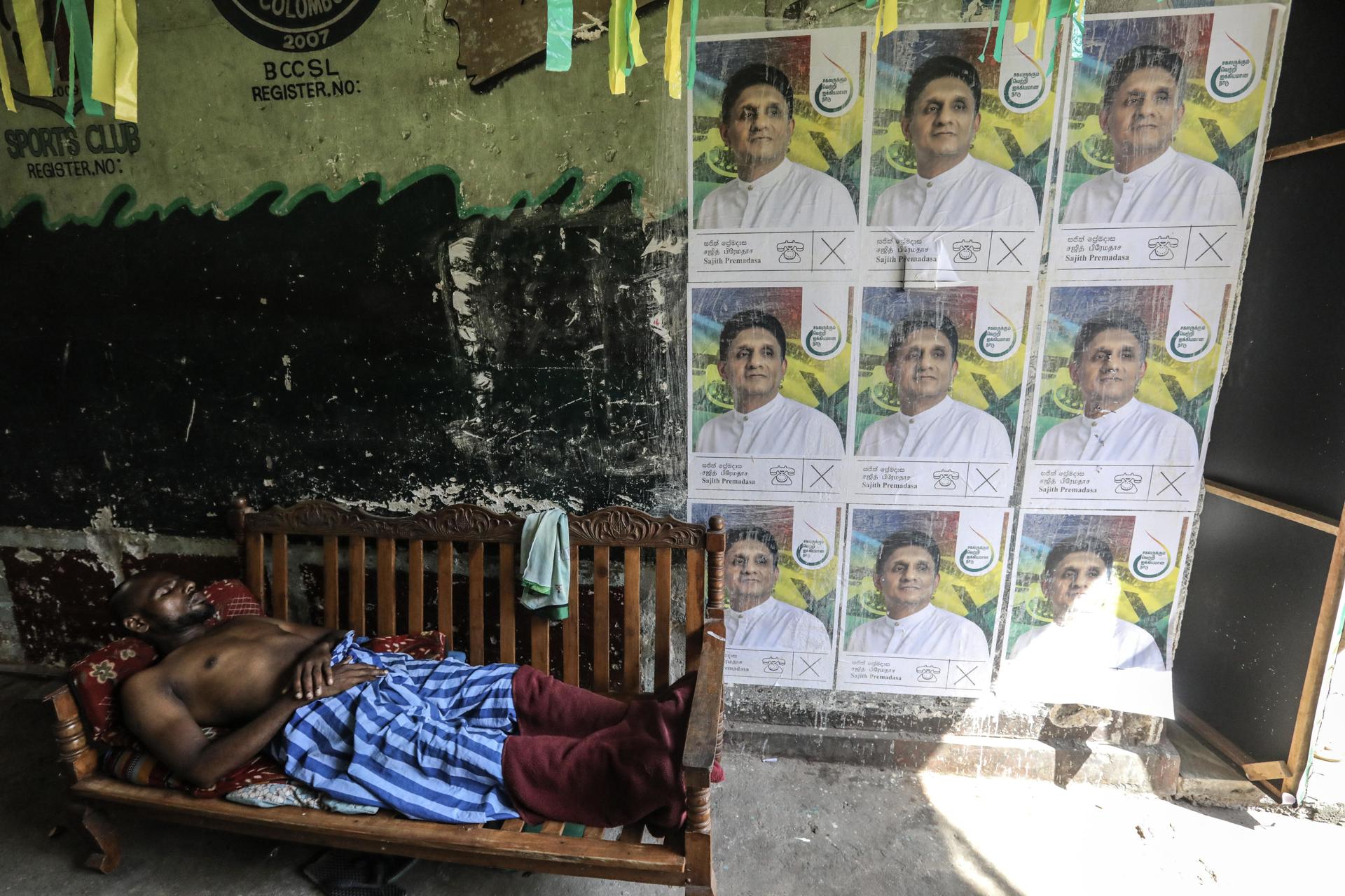 Un hombre duerme junto a una pared cubierta con carteles electorales del candidato presidencial del principal partido de oposición de Sri Lanka, Samagi Jana Balawegaya (SJB), Sajith Premadasa, antes de las próximas elecciones presidenciales en Colombo, Sri Lanka, el 18 de septiembre de 2024. Sri Lanka celebrará sus elecciones presidenciales el 21 de septiembre de 2024, sus primeras elecciones desde que en 2022 se desencadenaron protestas masivas y una importante crisis política a raíz del colapso económico. Un total de 39 candidatos de partidos políticos reconocidos y grupos independientes han presentado sus nominaciones, y el actual presidente, Ranil Wickremesinghe, se postula para un segundo mandato. (Elecciones, Protestas) EFE/EPA/CHAMILA KARUNARATHNE
