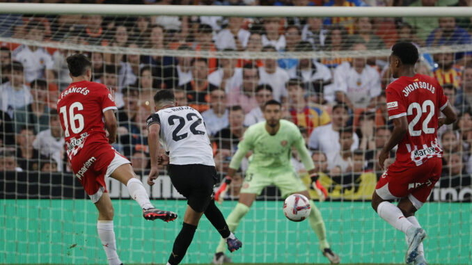 El delantero del Valencia, Luis Rioja, golpea el balón ante el guardameta argentino del Girona, Paulo Gazzaniga, para conseguir el primer gol del equipo valencianista durante el encuentro correspondiente a la sexta jornada de Laliga EA Sports jugado en el estadio de Mestalla, en Valencia. EFE/Manuel Bruque.
