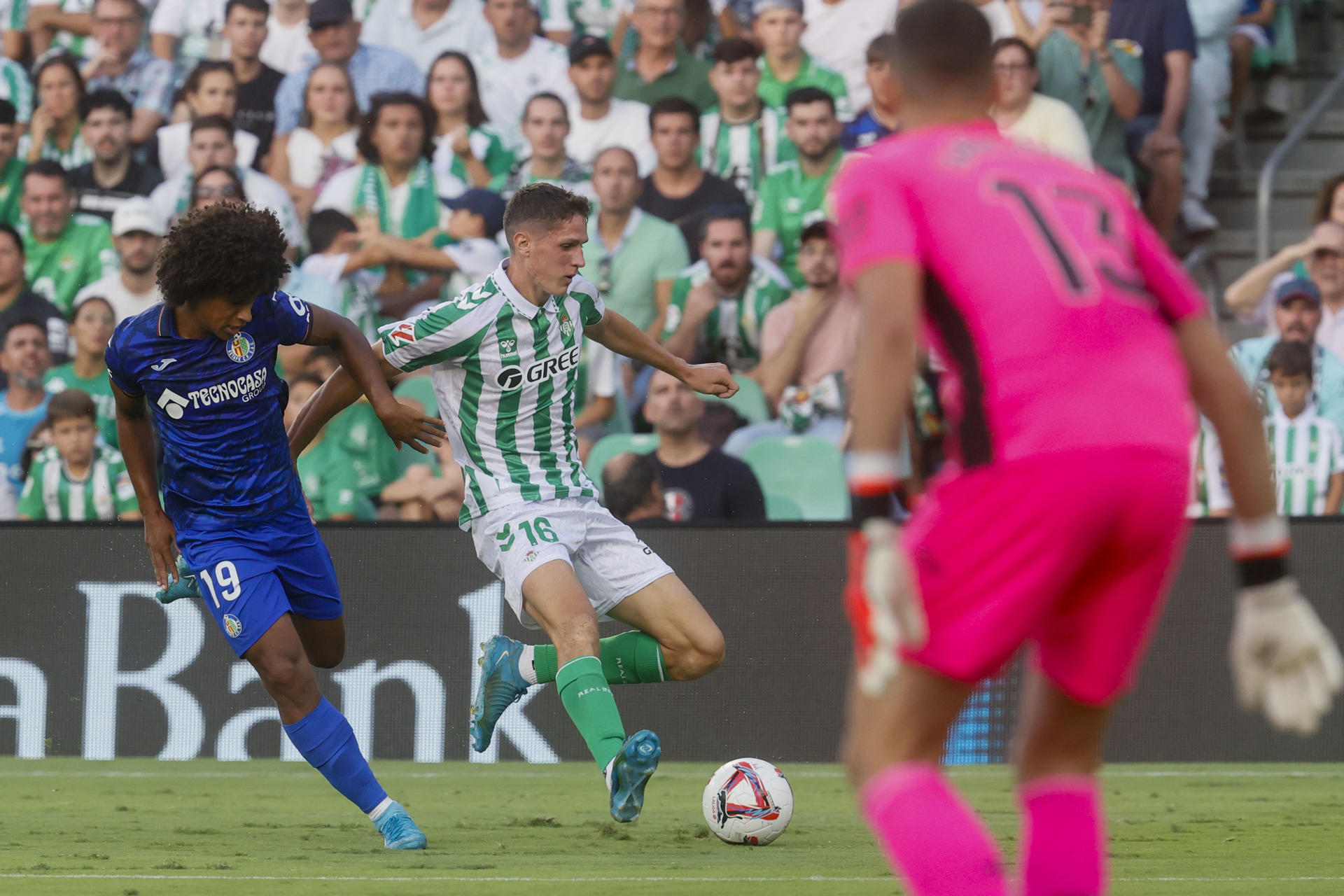 El centrocampista español del Betis Sergi Altimira (c) disputa un balón con el delantero hispano-dominicano del Getafe Peter González (i) durante el partido de la jornada 3 de LaLiga, en el estadio Benito Villamarín de Sevilla. EFE/ José Manuel Vidal
