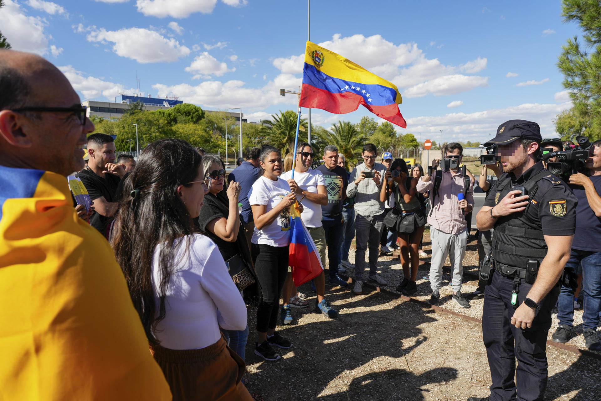 Simpatizantes del excandidato opositor a la Presidencia de Venezuela, Edmundo González Urrutia, conversan con un miembro de la Policía Nacional en la puerta de la base aérea de Torrejón de Ardoz (Madrid). Edmundo González Urrutia ha llegado a Madrid en un avión de las Fuerzas Aéreas españolas.-EFE/ Borja Sánchez-trillo
