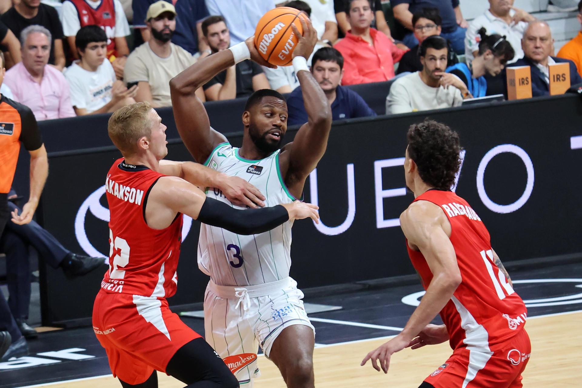 Melvin Ejim (c), de Unicaja, ante Hakanson (i) y Radebaugh del UCAM Murcia, durante el segundo partido de semifinales de la Supercopa Endesa que disputaron en el Palacio de los Deportes de Murcia. EFE/Juan Carlos Caval
