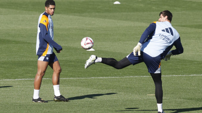 Thibaut Courtois (d) despeja el balón en presencia del centrocampista inglés Jude Bellingham. El portero belga ha sido incluido en la convocatoria para el partido ante el Celta de Vigo. EFE/Juan Carlos Hidalgo
