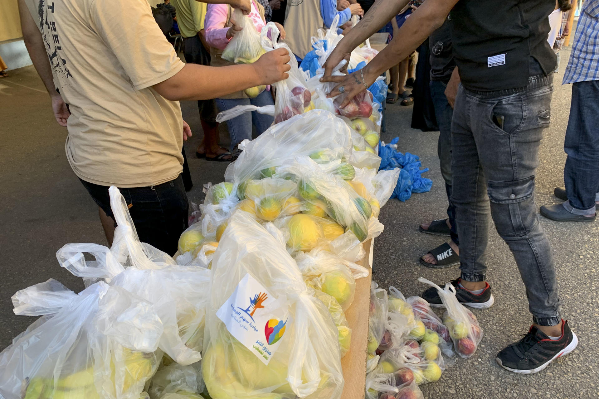 Bolsas con alimentos son repartidas a un grupo de desplazados en un colegio habilitado como albergue por la Agencia de la ONU para los Refugiados Palestinos (UNRWA) a las afueras de Sidón, en el sur del Líbano, ayer, martes 8 de octubre de 2024. Es este lugar, cientos de palestinos desplazados por la violencia israelí viven en la incertidumbre después de que la organización retirara repentinamente sus equipos y bandera de las instalaciones. EFE/Noemí Jabois
