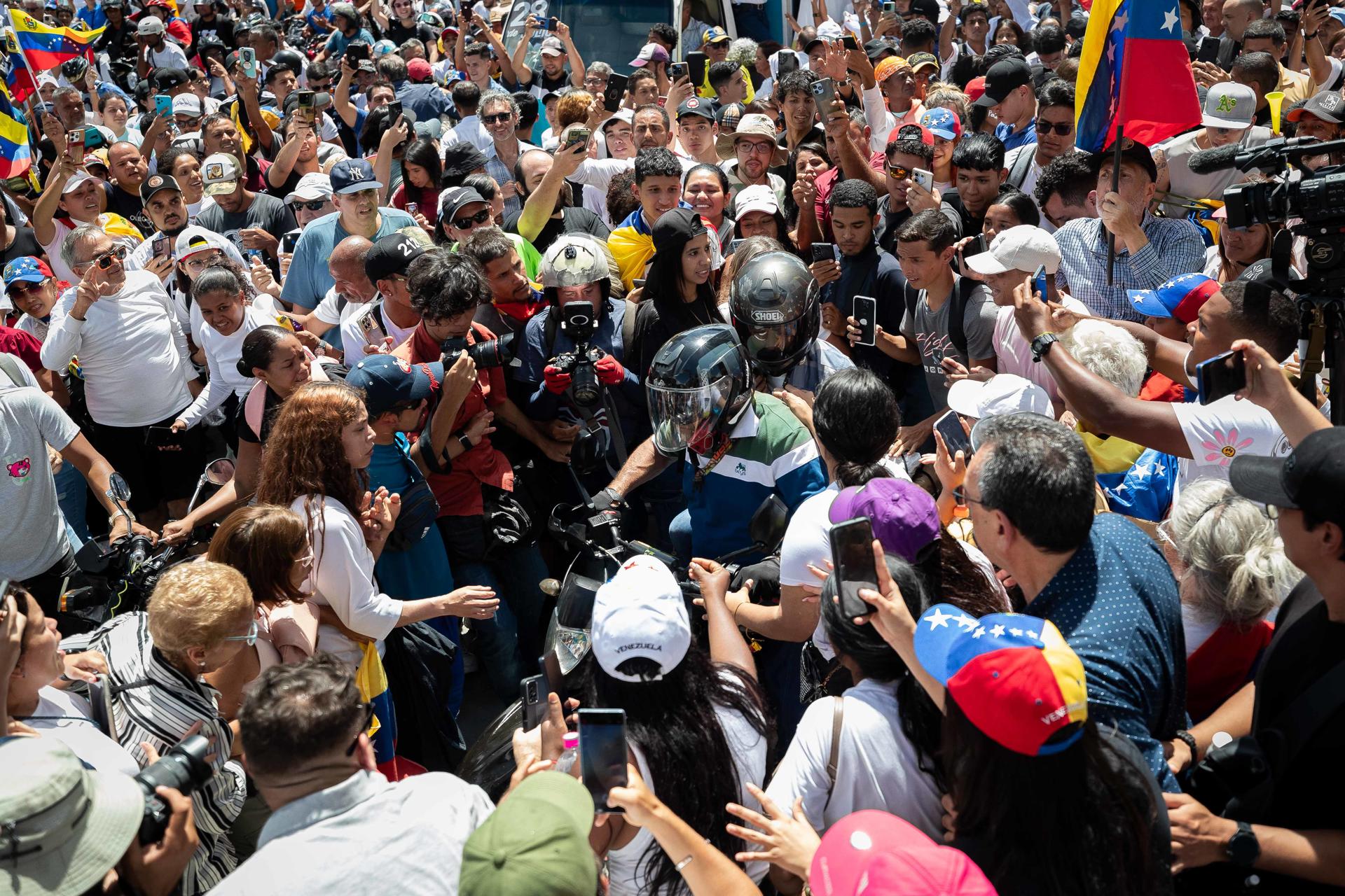 Fotografía del 3 de agosto de 2024 de la líder opositora venezolana, María Corina Machado (centro-atrás), retirándose en una motocicleta tras una protesta en la Plaza de las Mercedes, en Caracas (Venezuela). EFE/ Ronald Peña R.
