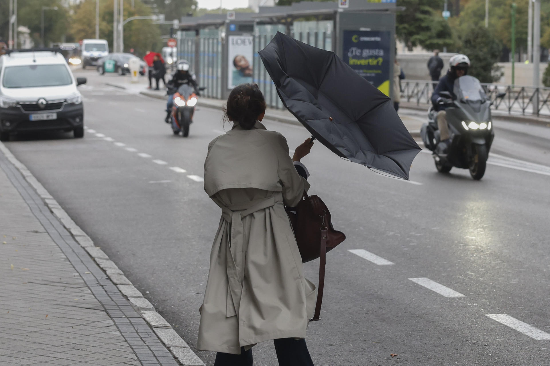 Una mujer lucha contra el viento que le ha dado la vuelta a su paraguas este miércoles en Madrid. EFE/ Juan Carlos Hidalgo
