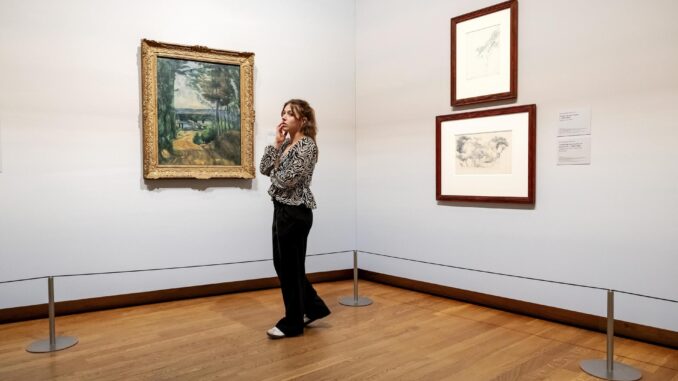 Una mujer contempla las obras 'El camino del lago' y 'Estudio de un árbol y paisaje con árboles y edificios' de Paul Cezanne, de la nueva exposición Vive l'impressionnisme! en el Museo Van Gogh de Ámsterdam, 09 de octubre de 2024. La exposición muestra las mejores obras impresionistas francesas de colecciones holandesas. (Países Bajos; Holanda) EFE/EPA/ROBIN VAN LONKHUIJSEN
