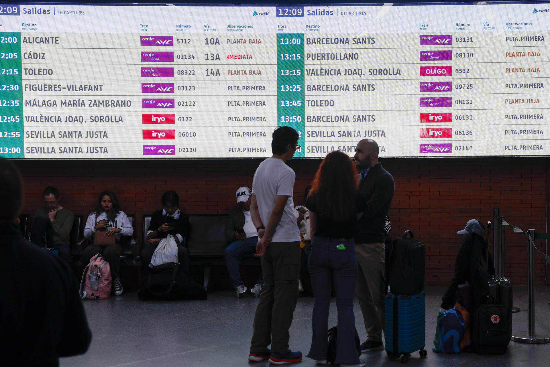 Varias personas esperan la salida de su tren en la estación de Atocha en Madrid este domingo. Renfe ha suprimido este domingo diversos trenes entre Madrid, la Comunitat Valenciana y Murcia debido a una incidencia con un tren sin pasajeros ocurrida ayer sábado en el túnel de alta velocidad que une las estaciones madrileñas de Atocha y Chamartín. EFE/ Sergio Pérez
