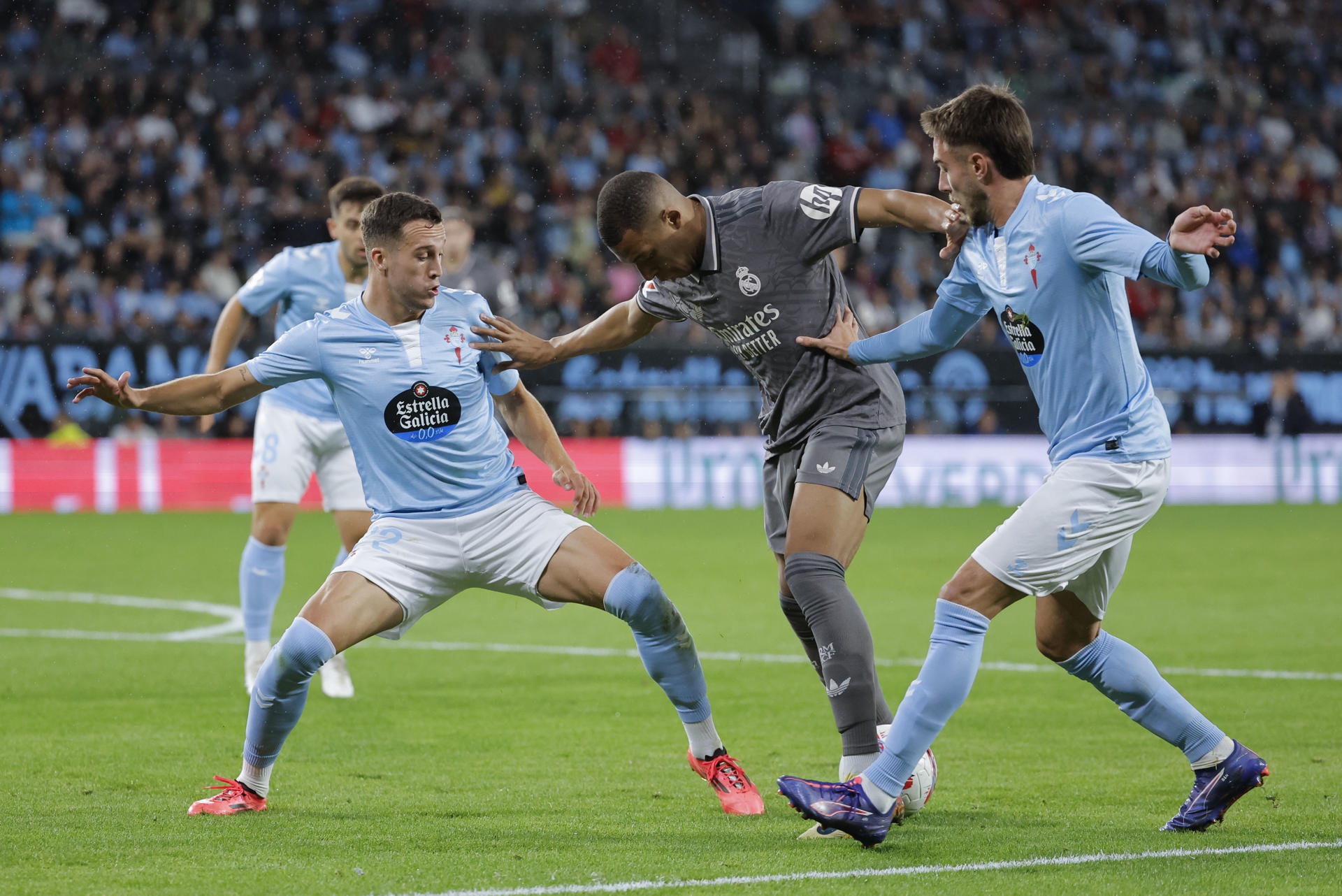 - El delantero del Real Madrid Kylian Mbappé (c) juega un balón entre Óscar Mingueza (d) y Javier Manquillo, ambos del Celta, durante el partido de la décima jornada de LaLiga EA Sports en el estadio de Balaídos. EFE/Lavandeira
